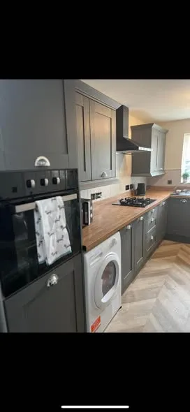 Fitted grey kitchen with wood-effect worktops. Photo 2 of 4.