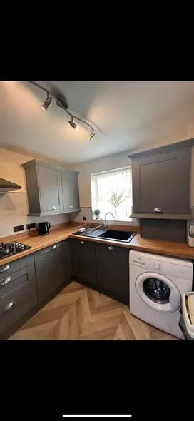 Fitted grey kitchen with wood-effect worktops. Photo 3 of 4.