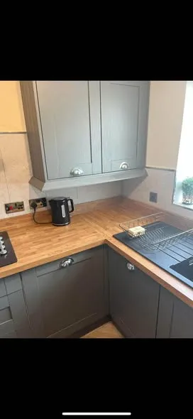 Fitted grey kitchen with wood-effect worktops. Photo 4 of 4.