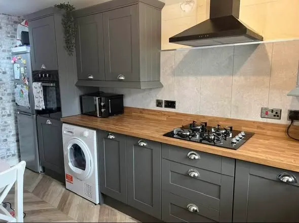 Fitted grey kitchen with wood-effect worktops. Photo 1 of 4.
